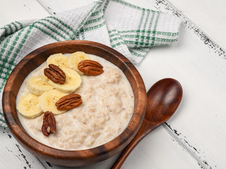 Oatmeal porridge with banana and pecan nuts for breakfast