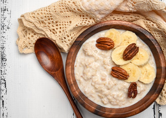 Oatmeal porridge with banana and pecan nuts for breakfast