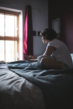 Woman using mobile phone in bedroom