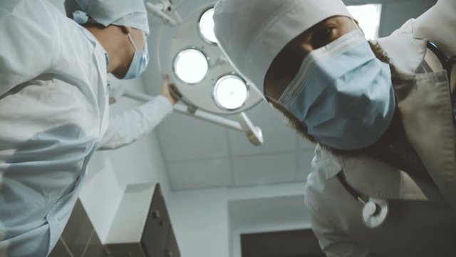 Low shot of doctor and nurse looking into a camera on patient