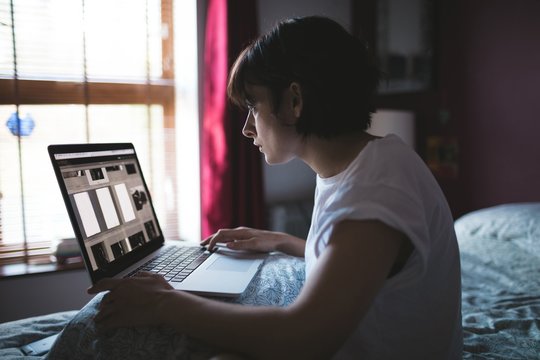 Woman using laptop in bedroom