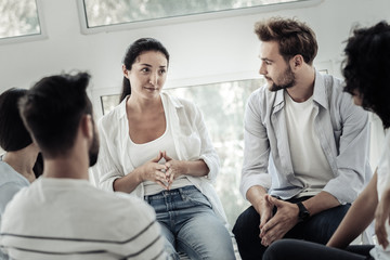 Effective therapy. Nice positive young people sitting together and looking at each other while having a group session