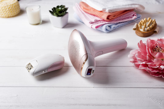 Modern laser epilator with bath accessories on white background.