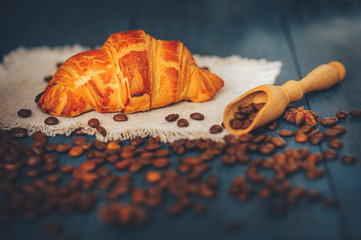 black, strong coffee with croissants on a light napkin, with cinnamon and anise on a blue table with a wooden texture, rest in a coffee house