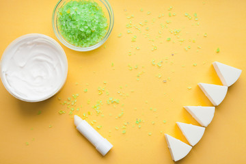 Skin treatment. Cream, soap and other cosmetics on the yellow background. Top view. Space for your text.