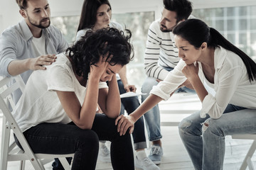 What to do. Depressed nice young woman holding her head and feeling unhappy while visiting a group therapy session