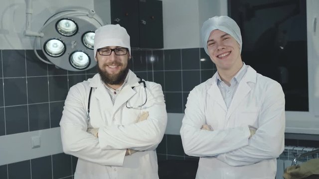 Portrait of two successful, cheerful and handsome doctors with crossed hands