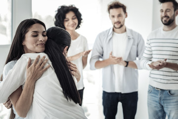 Warm feelings. Delighted positive young women smiling and hugging each other while expressing their warm feelings