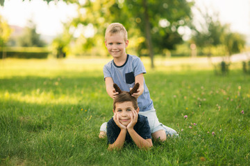 Two children are playing in the park. Two beautiful boys in T-shirts and shorts have fun smiling. They eat ice cream, jump, run. Summer is sunny