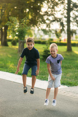 Two children are playing in the park. Two beautiful boys in T-shirts and shorts have fun smiling. They eat ice cream, jump, run. Summer is sunny