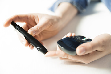 Diabetes checking blood sugar level. Woman using lancelet and glucometer at home