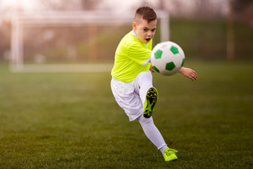 Obraz premium Boy kicking football on the sports field