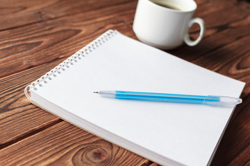 Office desk table top view. Notepad with blank pages on wooden table