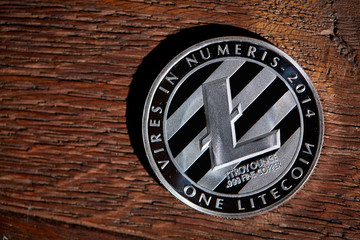 Silver coin of digital crypto currency with the symbol of Litecoin on a wooden background, close-up, macro