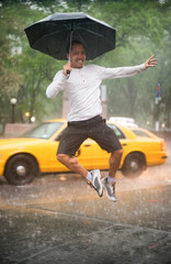 A man jumping in New York City's Central Park jumping in the rain with a big smile