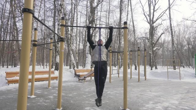 Man training pull up exercise with fitness expander on outdoor sport ground