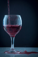 bright beautiful red wine pouring jet into a transparent glass cup isolated on a wite background