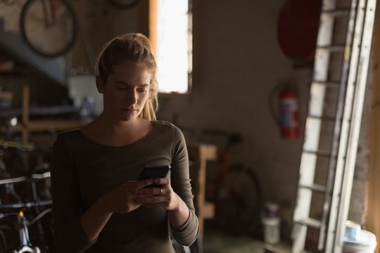 Female mechanic using mobile phone in workshop - Powered by Adobe