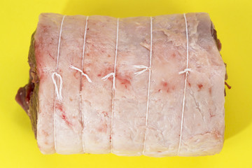 Joint of lamb for roasting on a yellow background