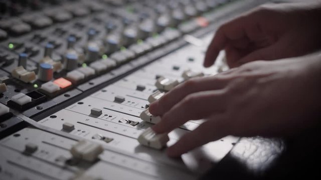 Close up shot of professional dj's hands working with a recording board in studio.