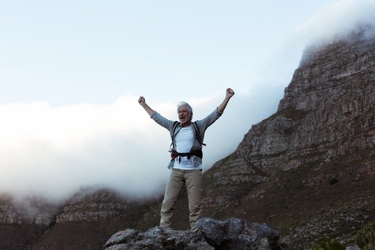 Senior Hiker Standing With Arms Up In Forest