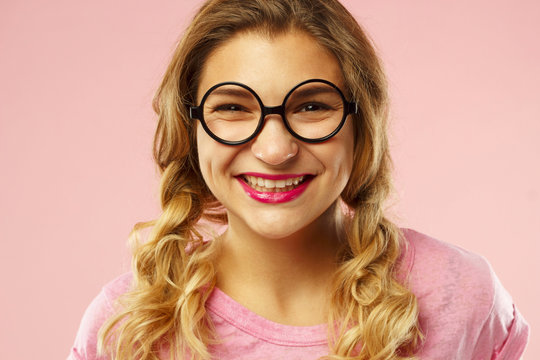 Portrait of a beautiful young woman in funny glasses over pink background