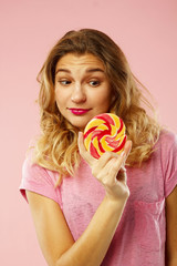 Portrait of a happy pretty girl holding sweet candy over pink background