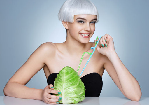 Funny smiling girl with cabbage cocktail on blue background. Detox concept