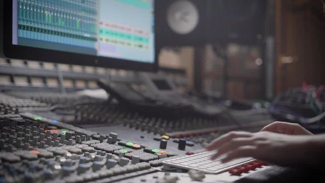 Talanted dj is creating music in a recording studio on a mixing console.