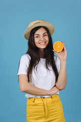 Brunette girl in yellow skirt holds oranges in her arms and smiles posing in the studio