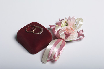 Wedding decor. Boutonniere bride, their wedding rings on box, lie on a white surface.