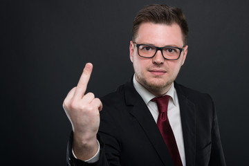 Portrait of business man wearing black suit showing obscene gesture.