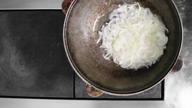 Close up shot of unrecognizable chef shaking dutch oven to stir chopped onions inside it, top view