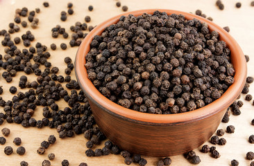 Pile of black pepper  in bowl on a wooden table