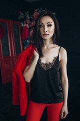 Fototapeta premium Woman in red suit stands before colorful flowers