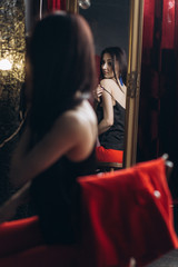 Obraz na płótnie Canvas Seductive woman takes off her clothes sitting before a mirror