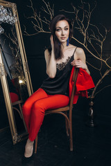Seductive woman in red suit sits before a mirror