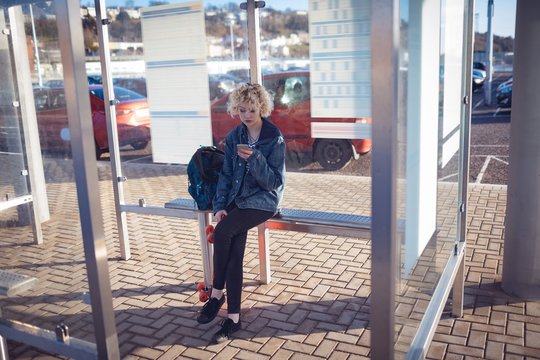 Woman using mobile phone at bus stop
