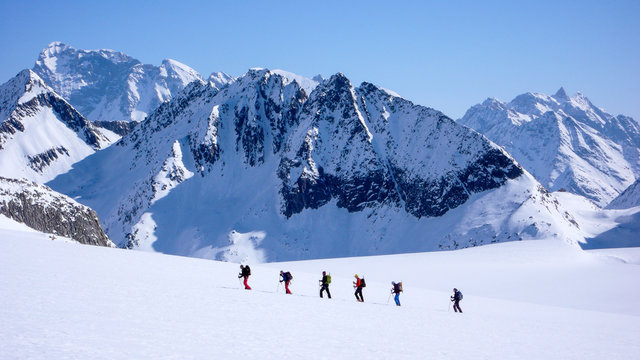group of backcountry skiers crossing a glacier on their way to a high summit in the Alps