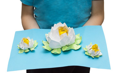 Very beautiful origami in child's hands: three white lotuses on the lake