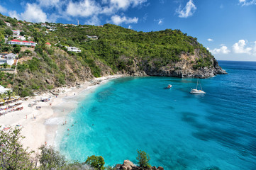 Obraz premium Harbor with sand beach, blue sea and mountain landscape in gustavia, st.barts. Summer vacation on tropical beach. Recreation, leisure and relax concept. Wanderlust and travel with adventure.