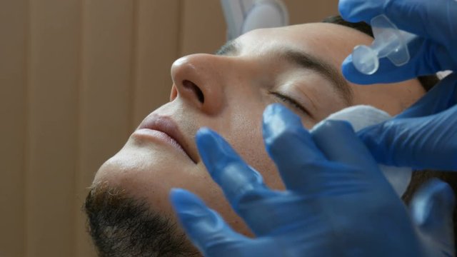 Filler injection for male face. Cosmetic surgery facial in beauty clinic. Doctor hand in medical gloves with syringe injects drug.