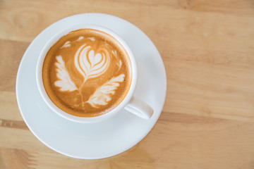 Hot milk latte art coffee on wooden table