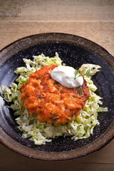 Salmon burger and cabbage salad in bowl on wooden table. Salmon fish cake and vegetables. vertical