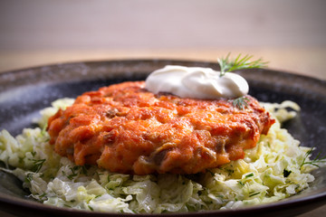 Salmon burger and cabbage salad in bowl on wooden table. Salmon fish cake and vegetables. horizontal