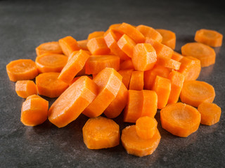 Pile of carrot slice over dark gray marble background.