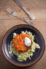 Salmon burger and cabbage salad in bowl on wooden table. Salmon fish cake and vegetables. overhead, vertical