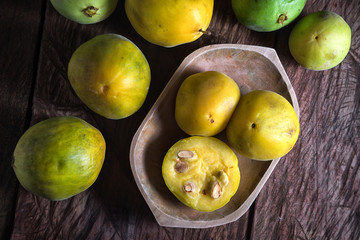 cut half rare araza fruits in a wooden bowl on rustic background