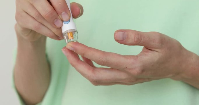 Woman self-testing for diabetes. Girls diabetic puncture finger to measure blood