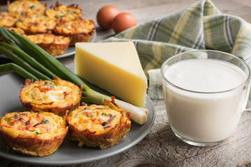 Muffins with scrambled eggs, cheese, bacon, potato and red pepper. Breakfast concept. Gray, rustic wooden background.